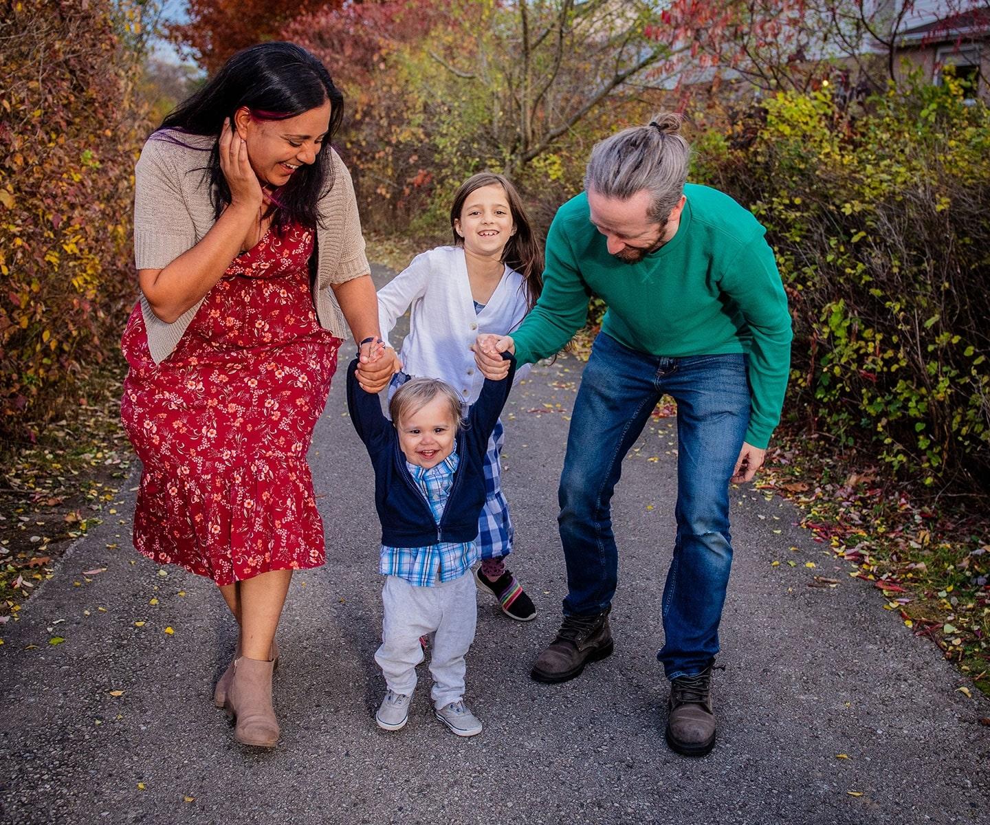 Toddler who received cord blood stem cells with mother, father and sister on a path outdoors 