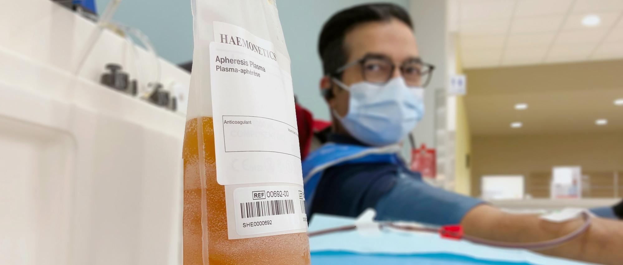 Ron Shivji looking at bag of plasma while donating plasma