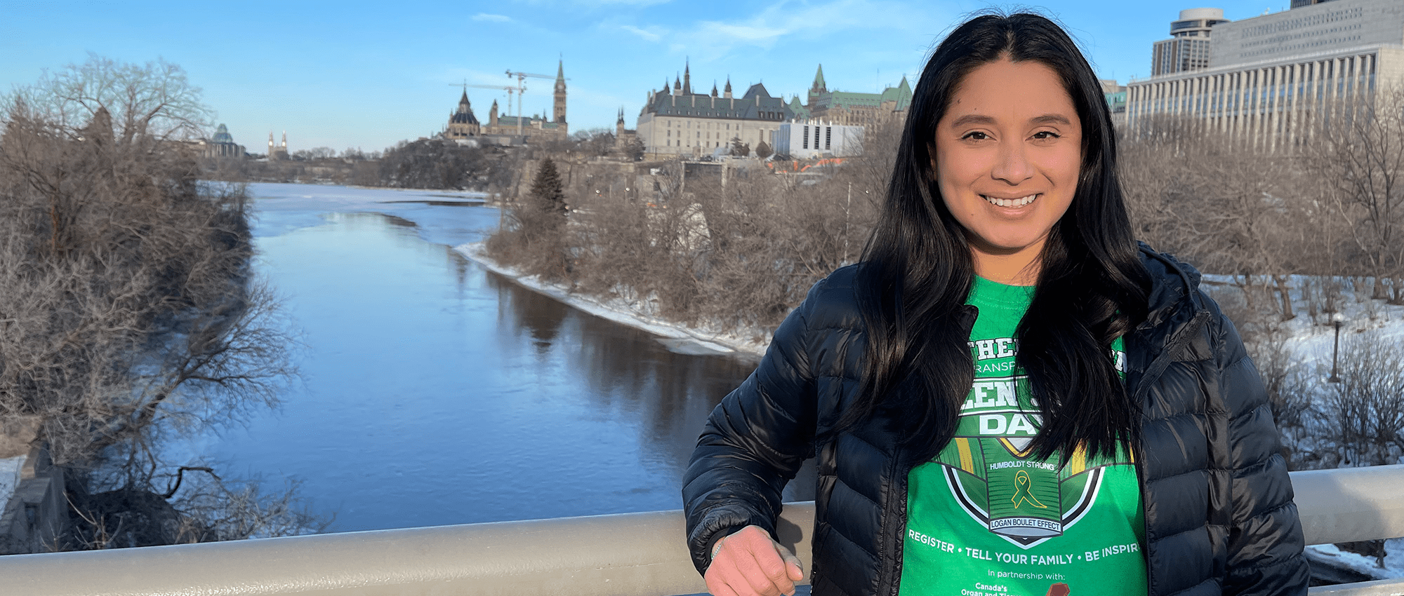 A woman in a green shirt stands on a bridge in Ottawa 